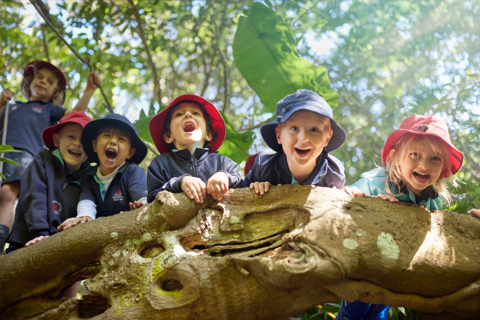 Early learning children outdoors on a tree trunk